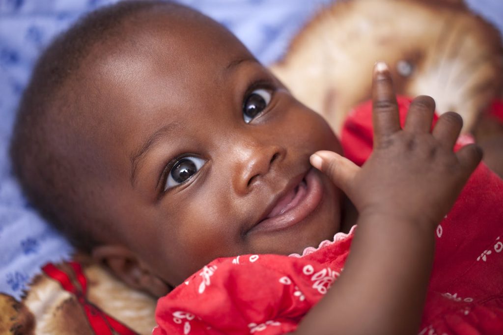 baby child kid girl 161593 Close-up portrait of a happy baby smiling in a bright red outfit, showcasing joy and innocence.